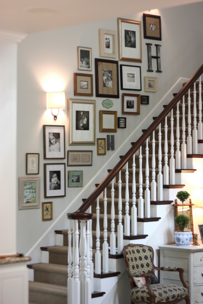 Escalera de diseño de pared con muchas fotos y una lámpara, sillón con diseño geométrico