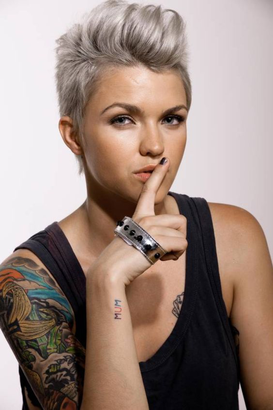 une femme rebelle avec des cheveux gris, des cheveux courts et des tatouages ​​colorés
