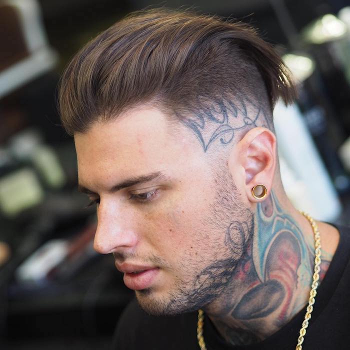 Το τατουάζ ανδρών Sidecut στο κεφάλι τους κάτω από το hairstyle που ταιριάζει με το στυλ τατουάζ