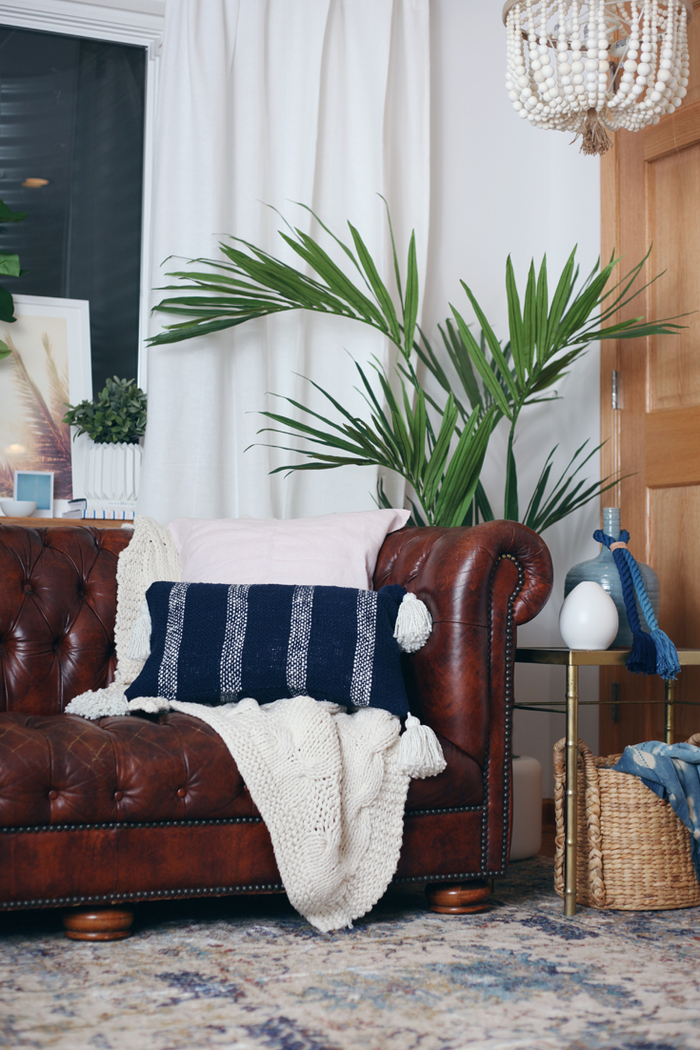 Decoración vintage, sofá de cuero, almohada decorativa azul, planta de interior grande, lámpara