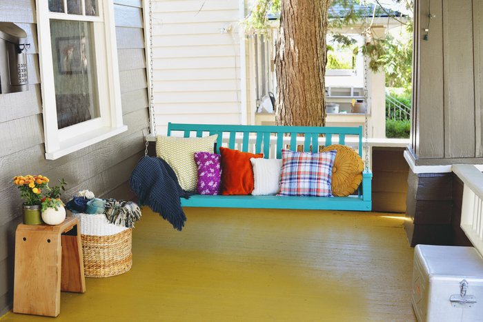 Terraza vintage, columpio con cojines decorativos, fresca y colorida, pequeñas plantas de balcón