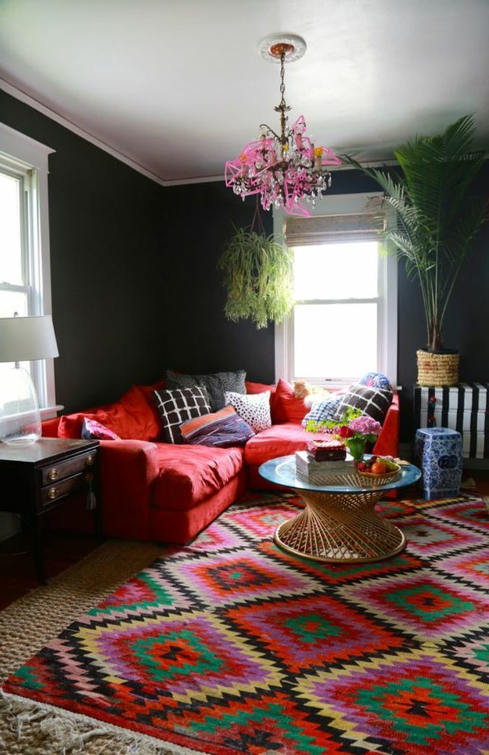 nappali színben színű falak színes kialakítás falak színes-mintás szőnyeg piros sarok-mintás párna kerek üveg asztal fa éjszakai lámpa-növény