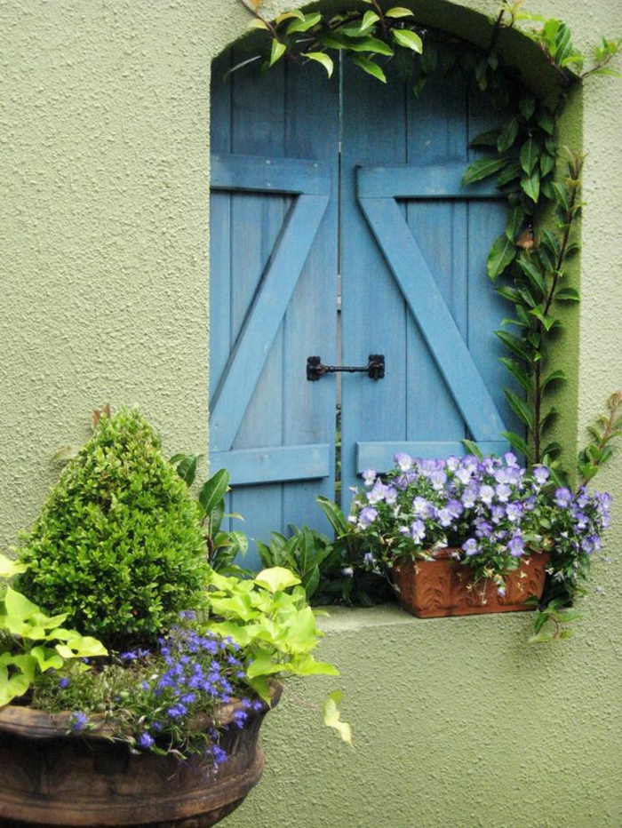 美丽的蓝色百叶窗花绿墙